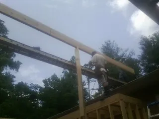 Carpenter setting a ridge beam over a new addition frame in Grapevine