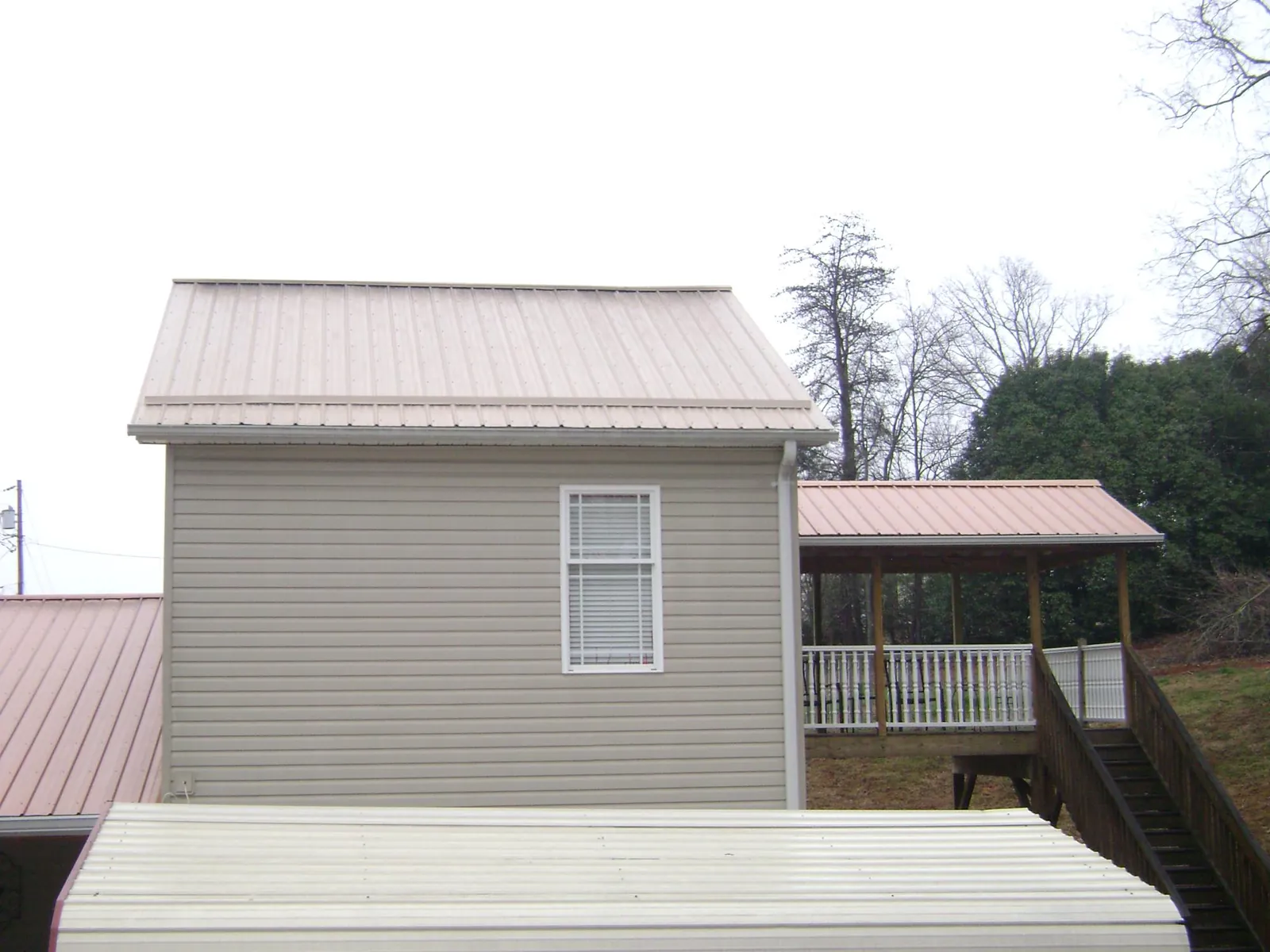 Tan metal roofs on a two story addition and attached porch, from a Roof Replacement job in Grapevine
